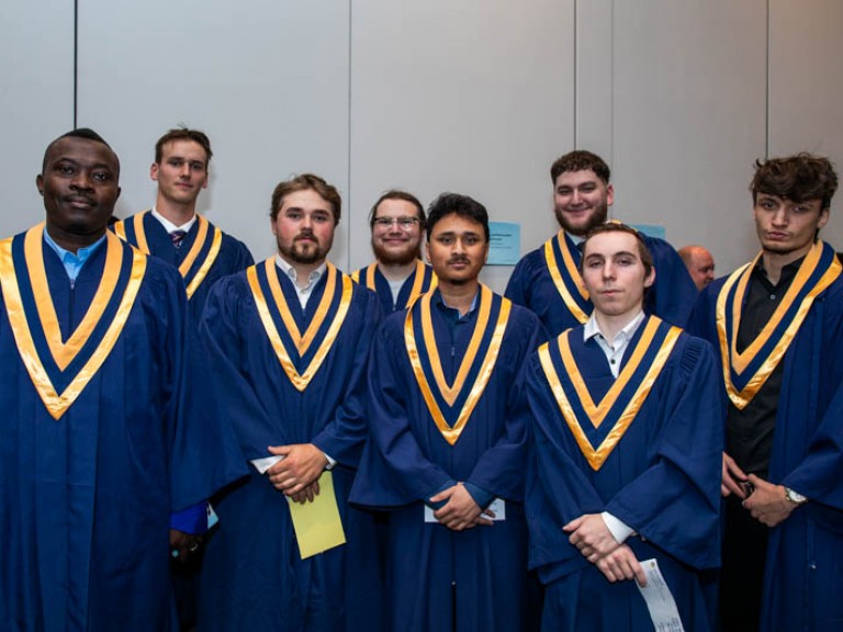 Eight graduates pose for photo