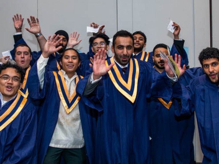 Ten graduates raise their hands in celebration