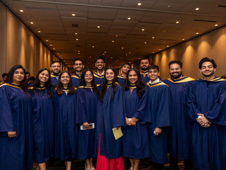 Fourteen graduates stand for photo