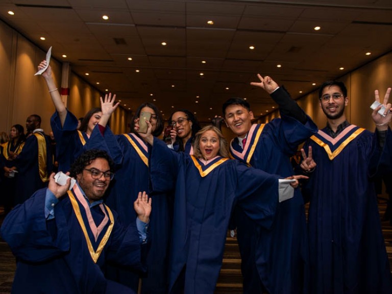 Seven graduates raise arms in celebration