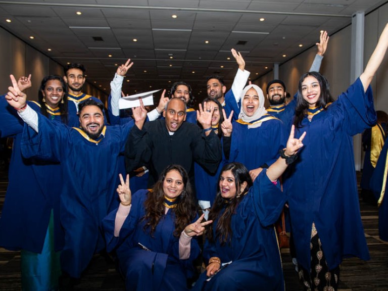 Group of graduates raise arms in celebration