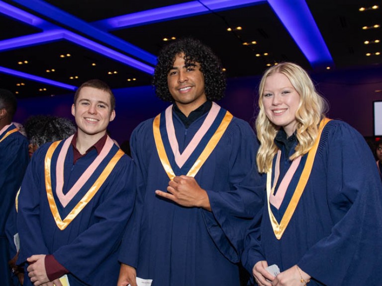 Three graduates smile at camera