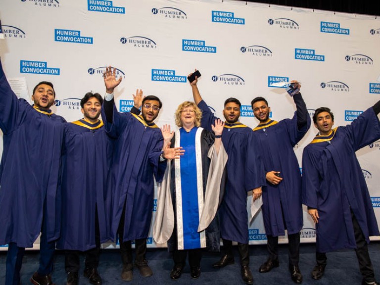 Six graduates and Ann Marie Vaughan raise arms in celebration