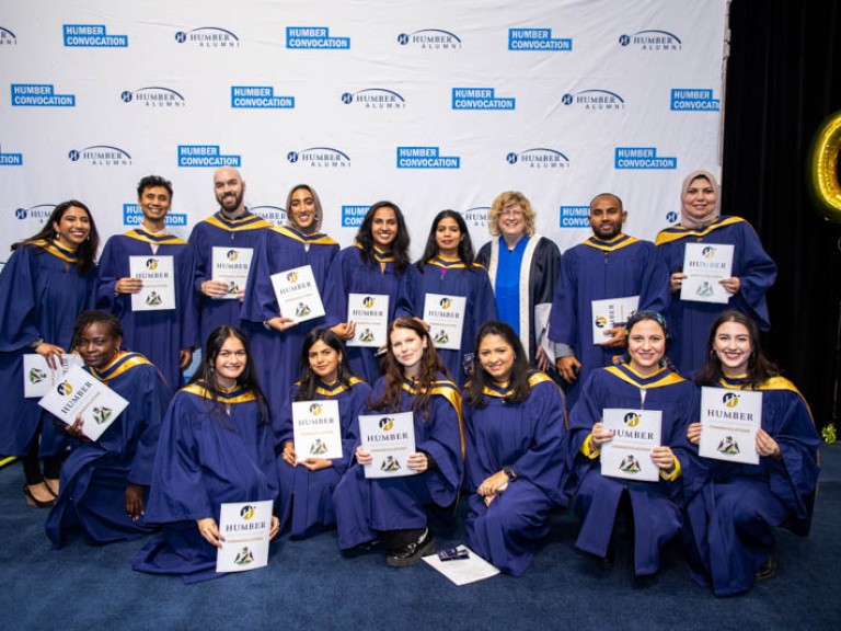 Group of graduates take photo with Humber president
