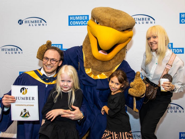 Humber mascot takes photo with a graduate and their family