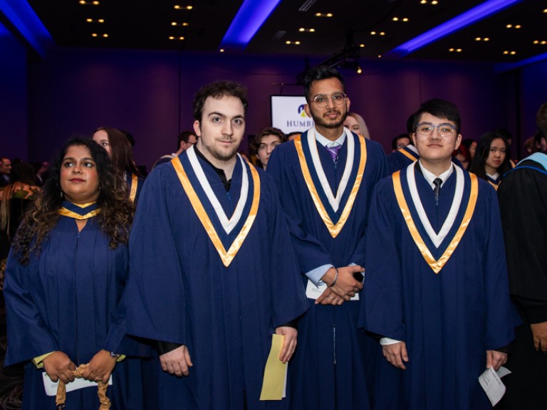 Four graduates standing in ceremony hall
