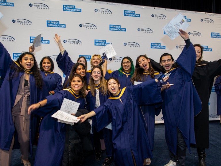 Group of graduates raise arms in celebration 