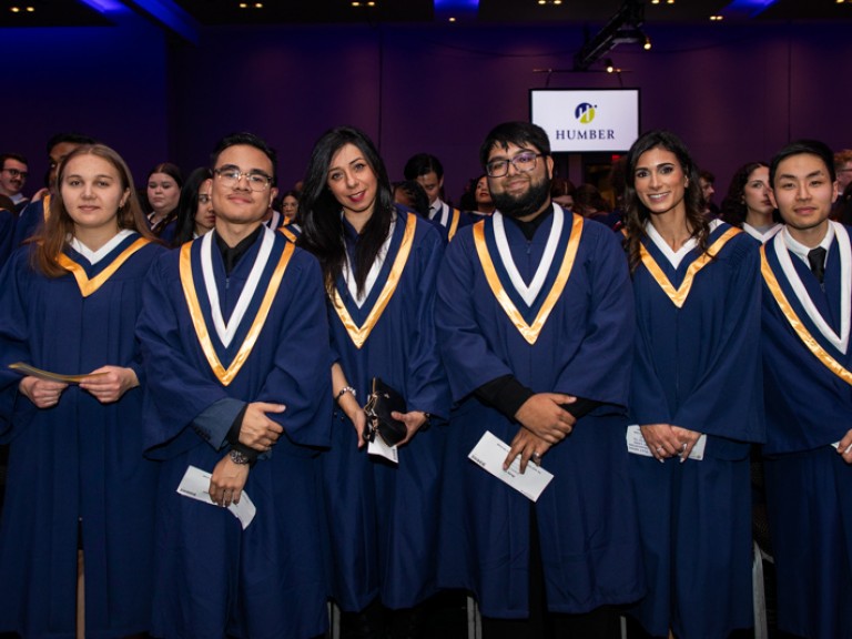 Row of graduates standing look at camera