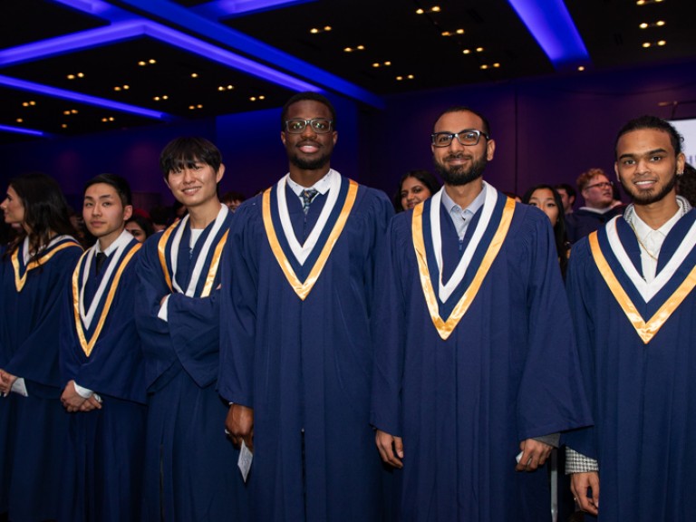 Graduates in ceremony hall pose for photo