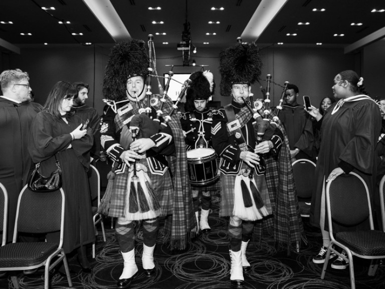 People in Scottish regalia play bagpipes as they walk down aisle
