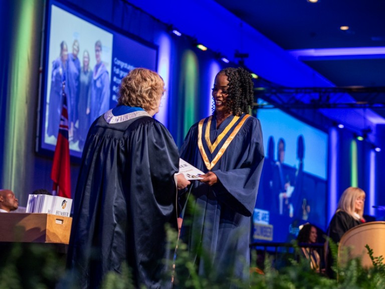 Graduate smiles as they accept certificate