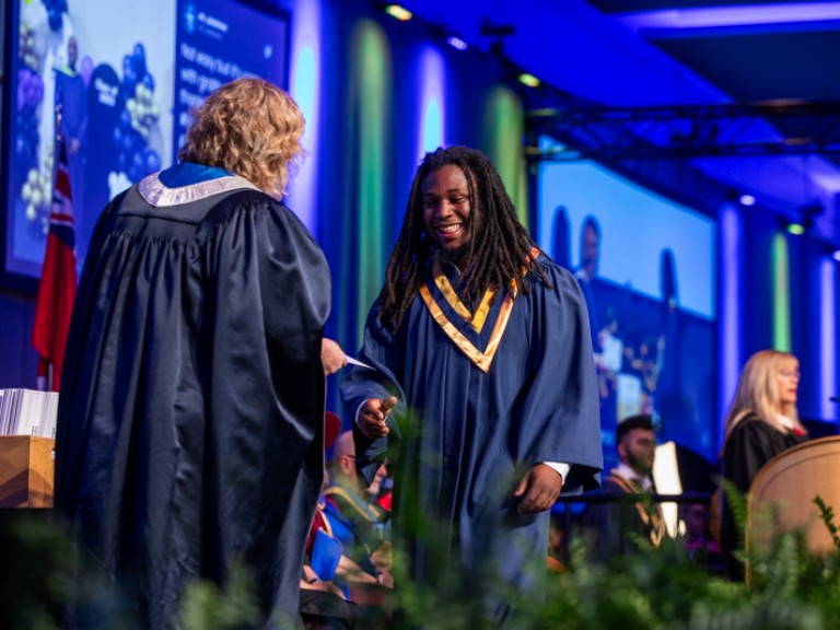 Graduate accepts certificate from Ann Marie Vaughan on stage