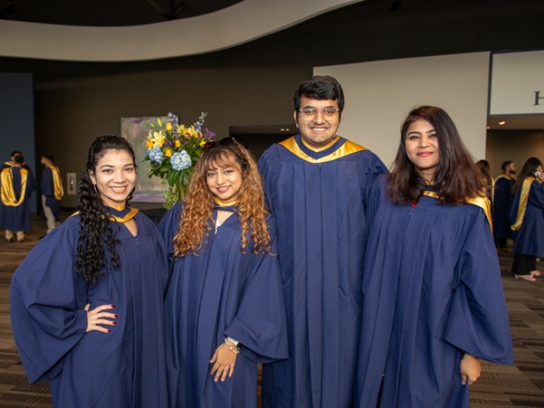 Four graduates smile for photo