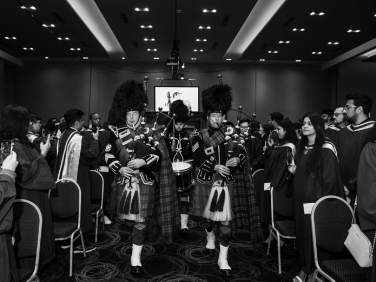 People in Scottish formalwear play bagpipes as they walk down aisle