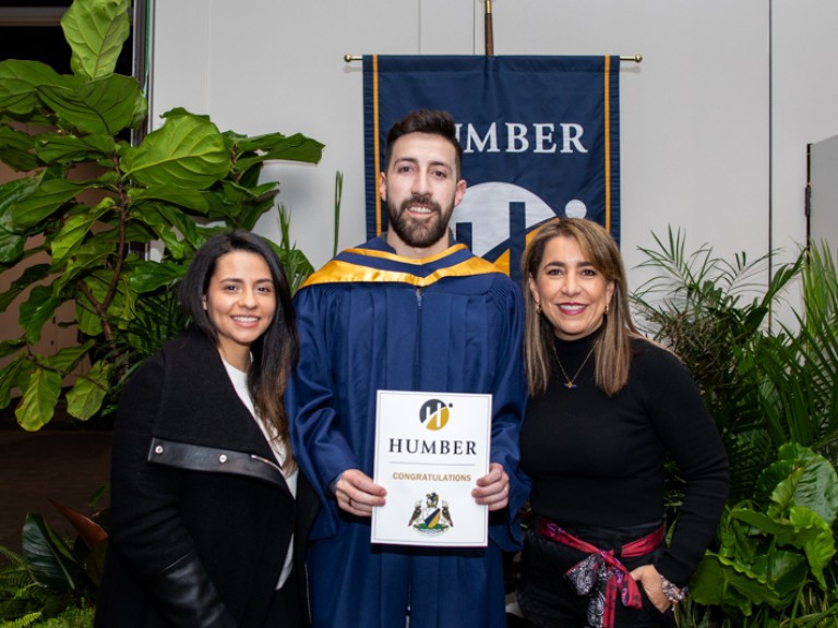 Graduate takes photo with two ceremony guests