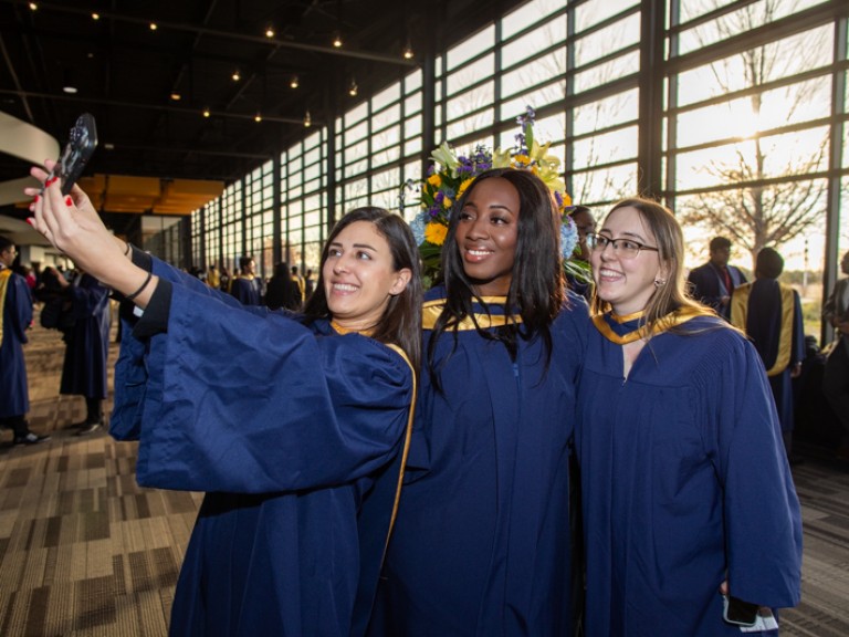Three graduates take a selfie together