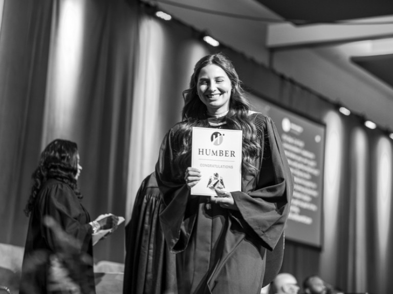 Graduate holding certificate with a smile