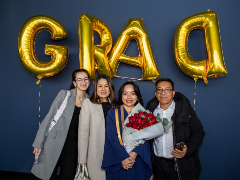 Graduate holding roses takes photo with family