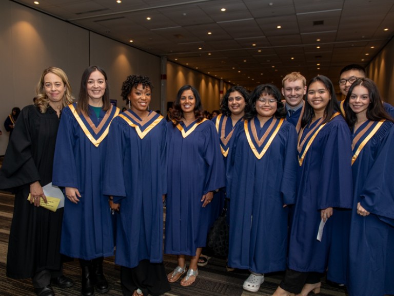 Nine graduates take photo with person in black robe