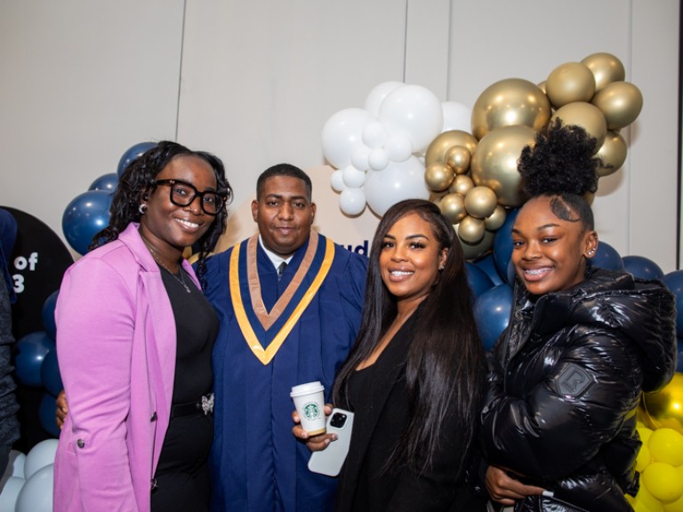 Graduate takes photo with three ceremony guests