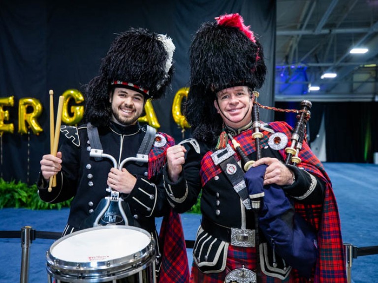 Two musicians in Scottish regalia smiling for photo