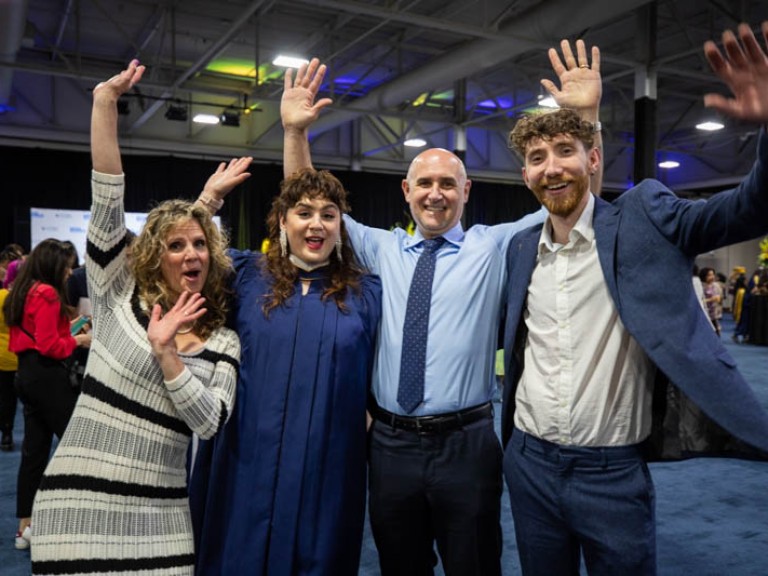 Graduate and family raising their arms for photo
