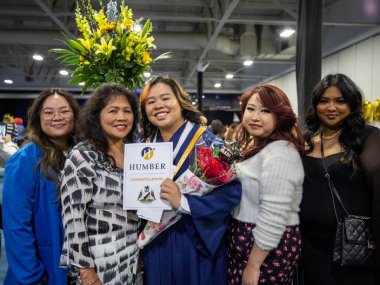 Graduate holding roses taking photo with family