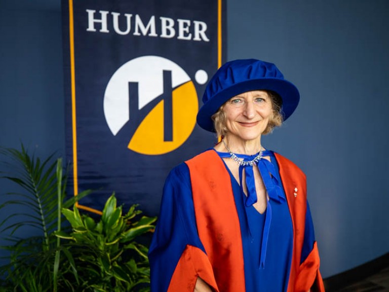 Honorary degree recipient Sara Diamond standing in front of Humber flag