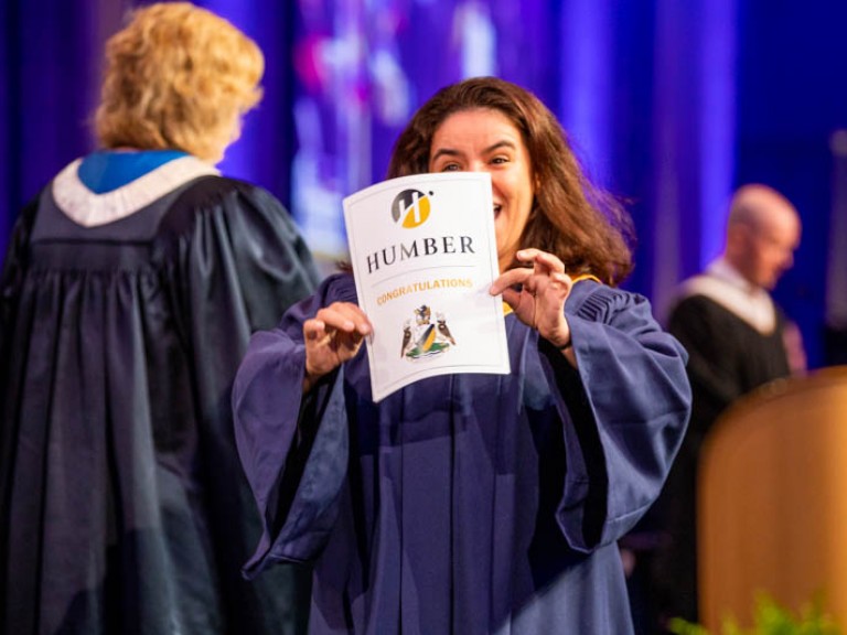 Graduate holding their certificate up as they cross the stage