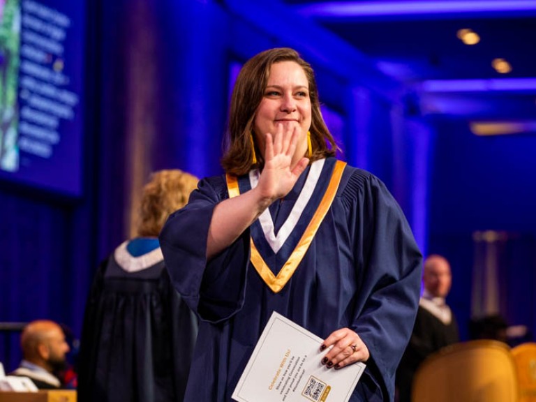 Graduate waving at someone