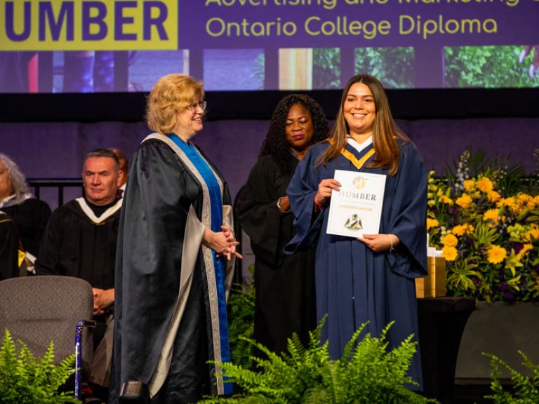 Humber graduate holding certificate on stage