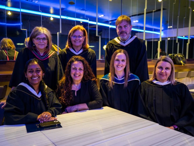 Humber faculty members in black robes posing for photo at a table