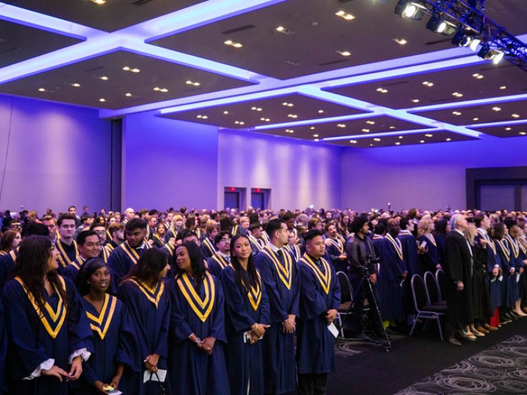 Ceremony hall with graduates standing in front of their seats