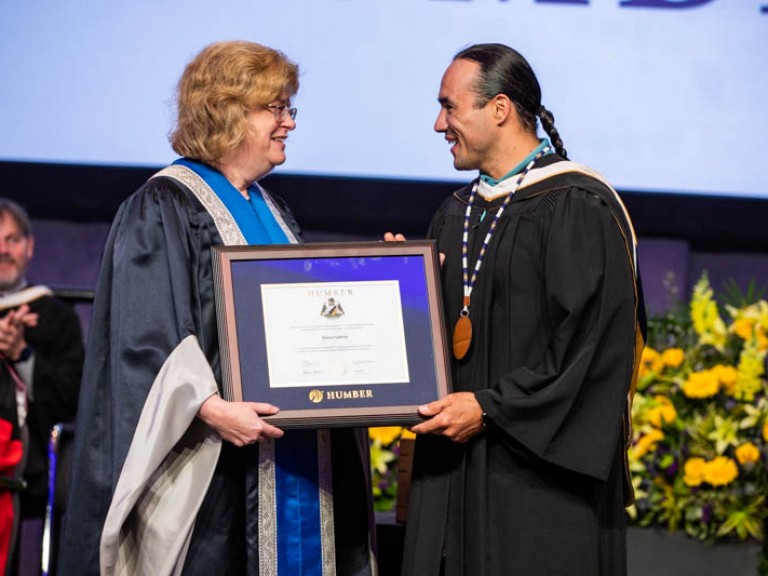 Michael Linklater accepts a framed degree from Humber president Ann Marie Vaughan
