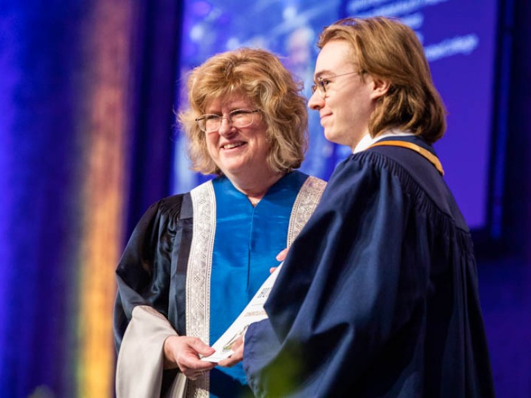 Ann Marie Vaughan and graduate holding certificate on stage