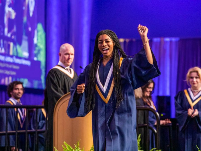 Graduate leaving stage with one arm raised in celebration