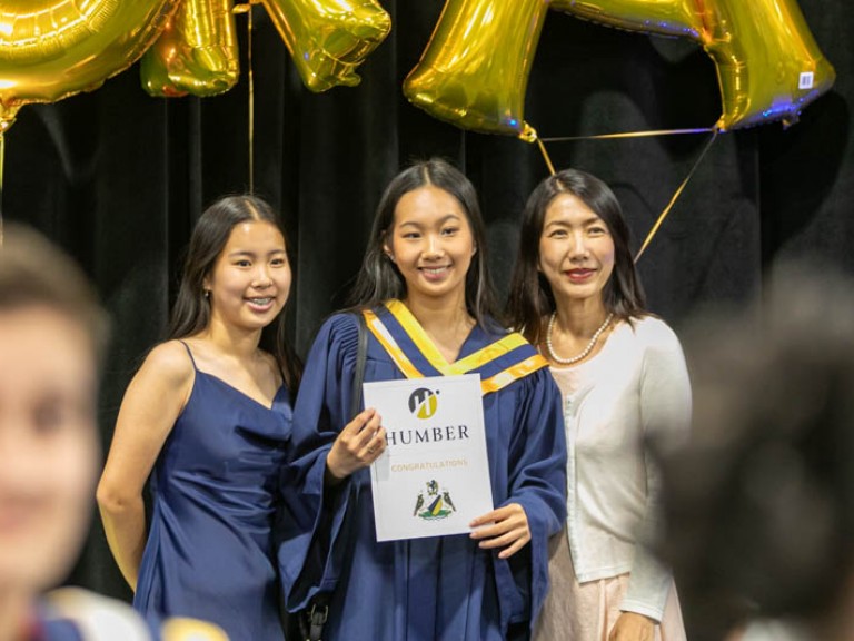 Graduate posing with two family members for photo