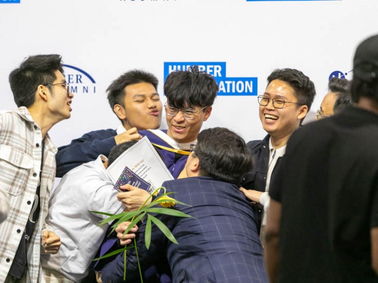 Graduate being hugged by friends