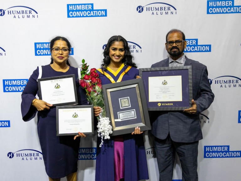 Graduate with parents holding framed awards
