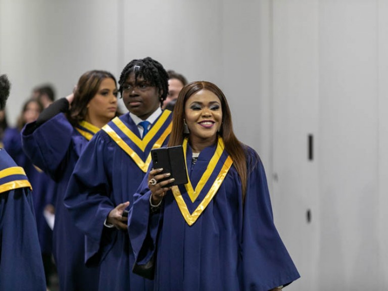 Smiling graduate holding a cell phone in the lineup