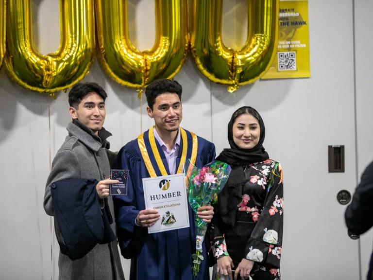 Graduate taking photo with two ceremony guests