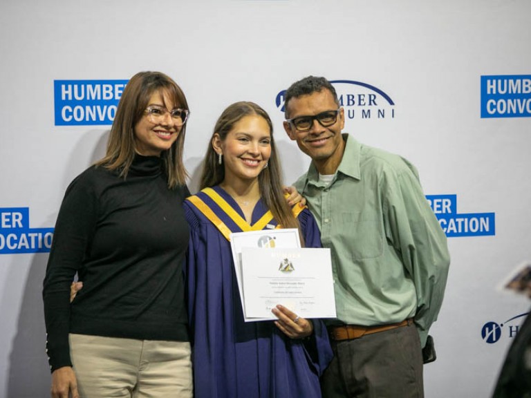 Graduate posing for photo with parents
