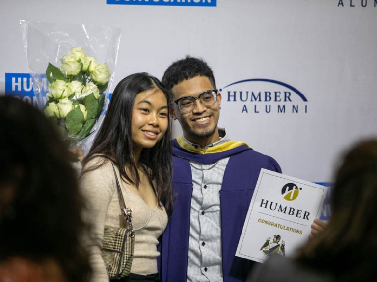 Graduate posing with photo with ceremony guest