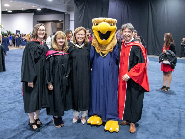 Four Humber faculty members pose for photo with Humber mascot