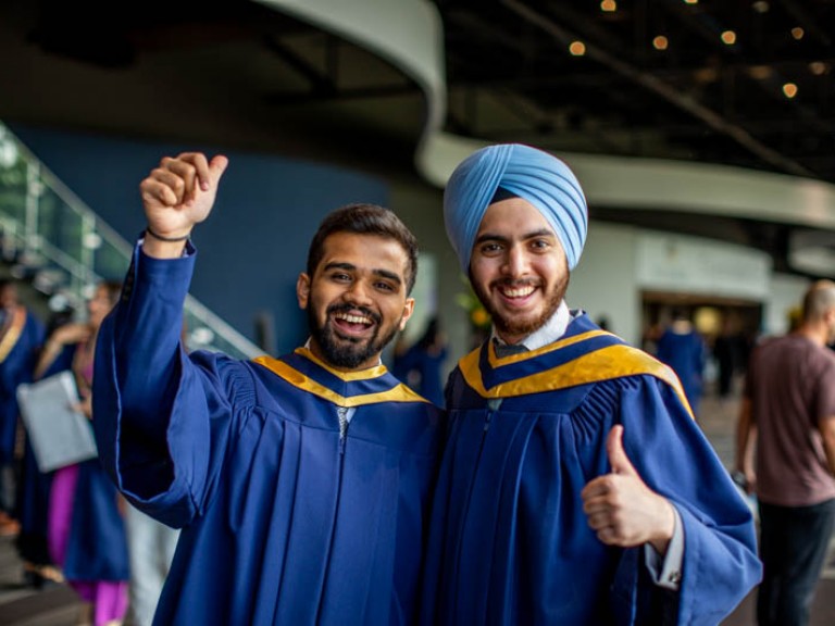 Two graduates smiling for photo in reception area