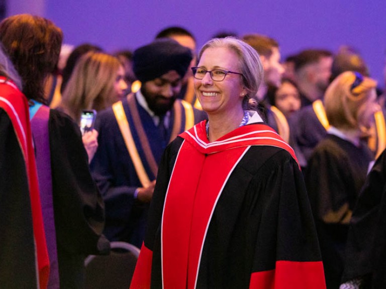 Faculty member smiling as they proceed into ceremony hall