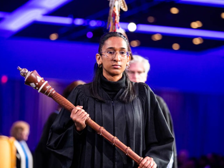 Person carrying staff in black gown