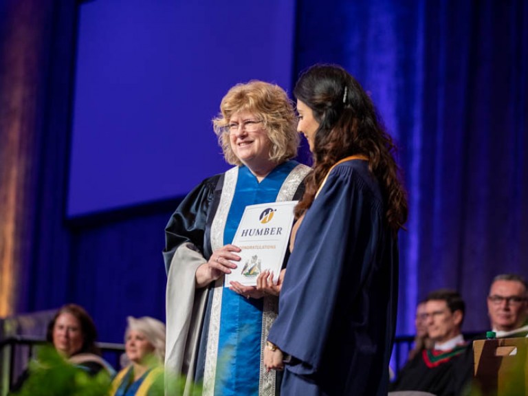 Ann Marie Vaughan holds certificate beside graduate on stage