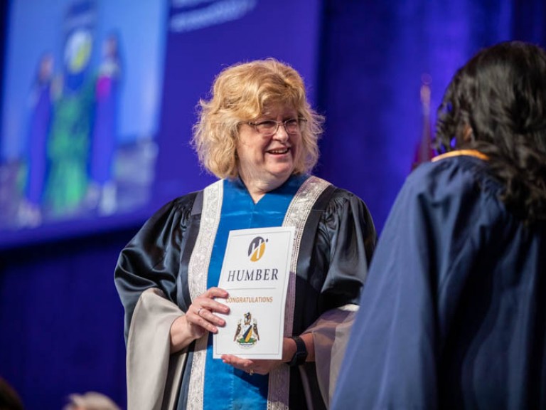 Ann Marie Vaughan holding certificate looking at graduate