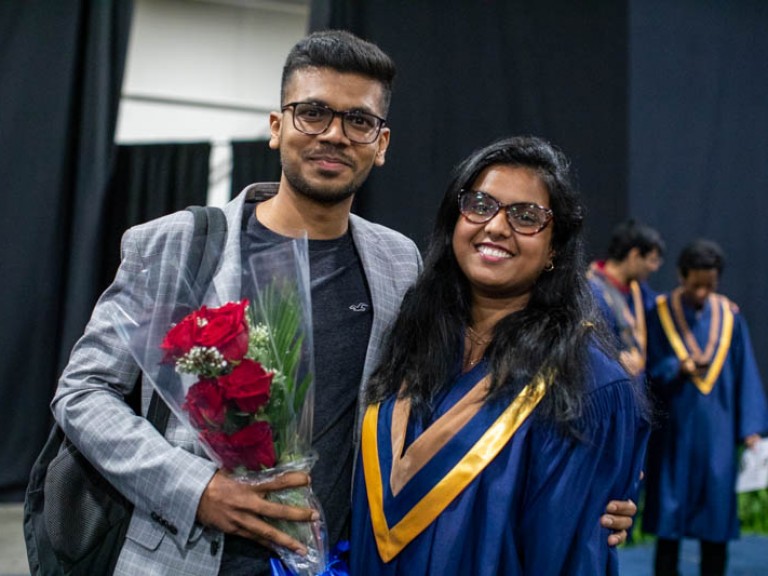 Graduate posing with ceremony guest for photo